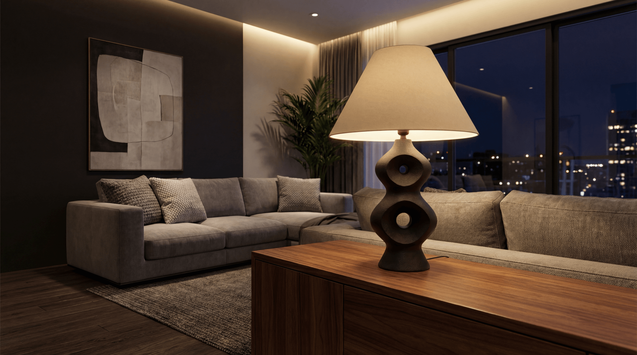 Dark sculptural table lamp with empire shade on a console table in a contemporary living room at night